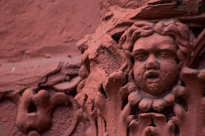 A worn architectural ornament, a pudgy face on a building.