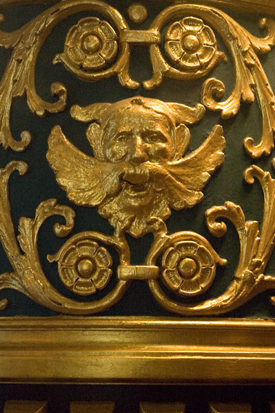 Flourishes and a face with a huge mustache, all gilt, on green.