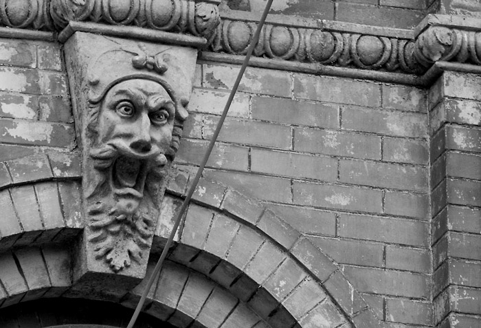 An architectural ornament face with crossed eyes, screaming.