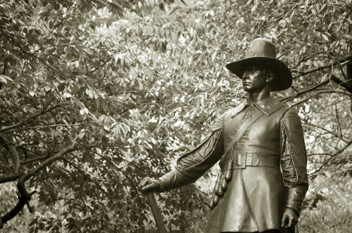 A statue of a male pilgrim, with a firm expression.