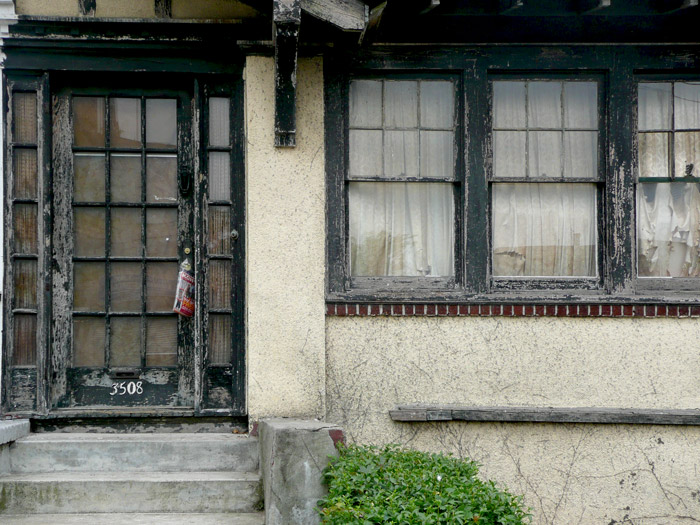 Paint peels on the weathered wood of a house.