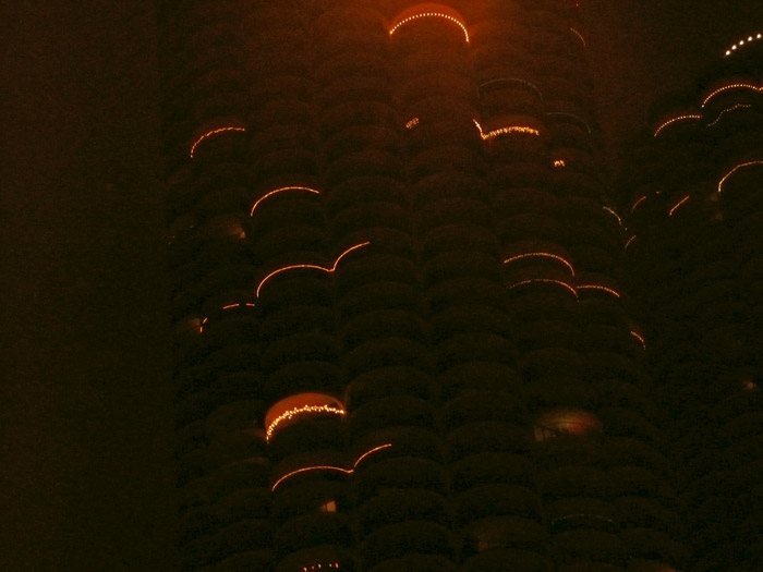 Holiday lights on the balconies of otherwise dark towers.