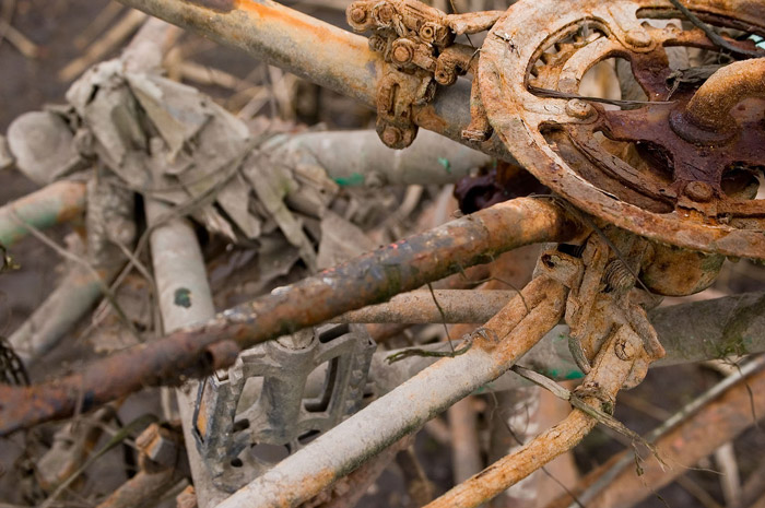 The rusting sprocket and pedals of an abandoned bike.