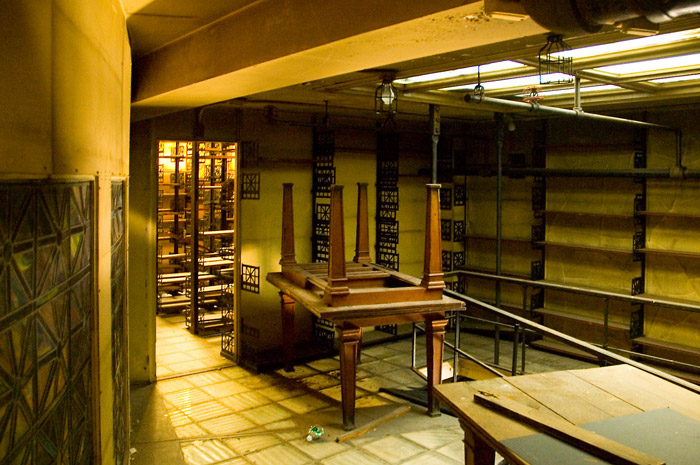 Stacked tables, empty shelves, and lots of dust in a room fallen out of use.