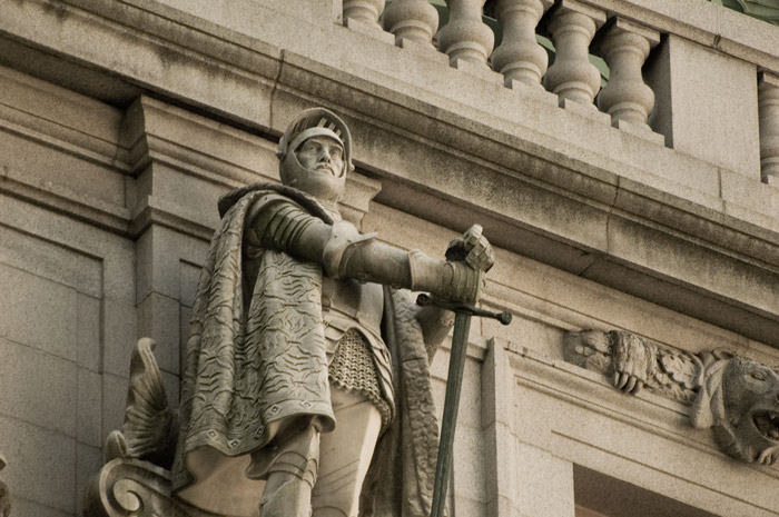 A statue of a helmeted soldier, holding a long sword.