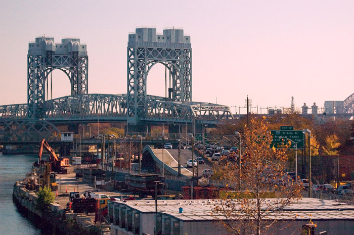 A bridge spans a river, with cars driving up to it.