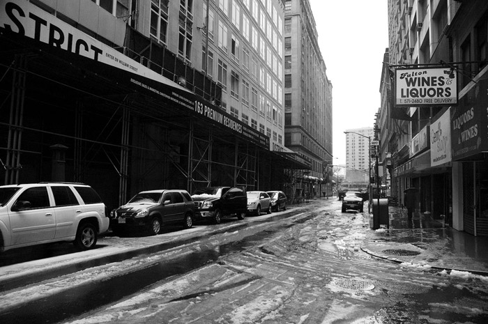 Slush from light snow lines a Manhattan street, on a dark block.