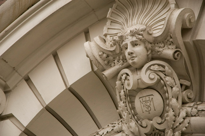 A young face, surrounded with ornamentation, is in an entrance arch.