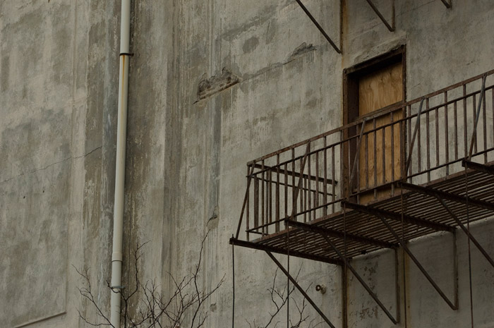 The boarded-up door of a building seems to stare out, pointlessly.