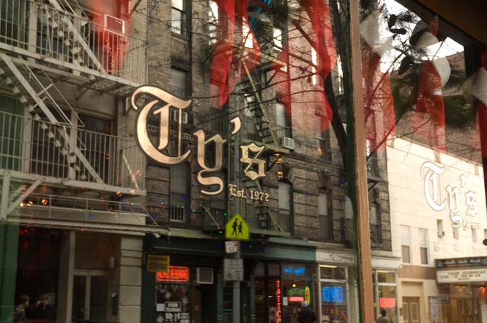 The bar's name is in gold leaf, on a window reflecting buildings across the street.