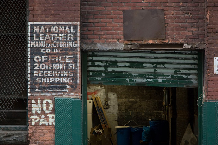 The door of an old shipping and receiving entrance is up, showing the company refrigerator, ladders, and sundry stuff.