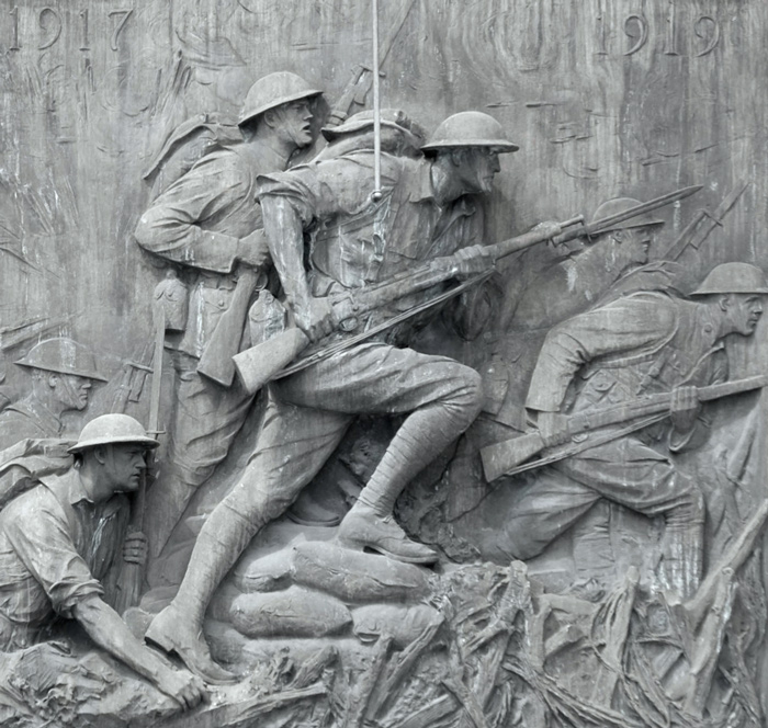 A relief, in metal, shows American soldiers pushing forward, with bayonettes on their rifles.