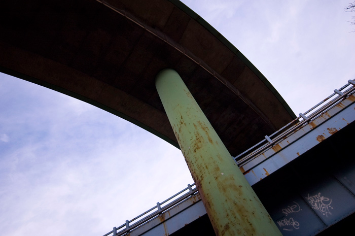 A ramp for a bridge arcs over a green support pillar.