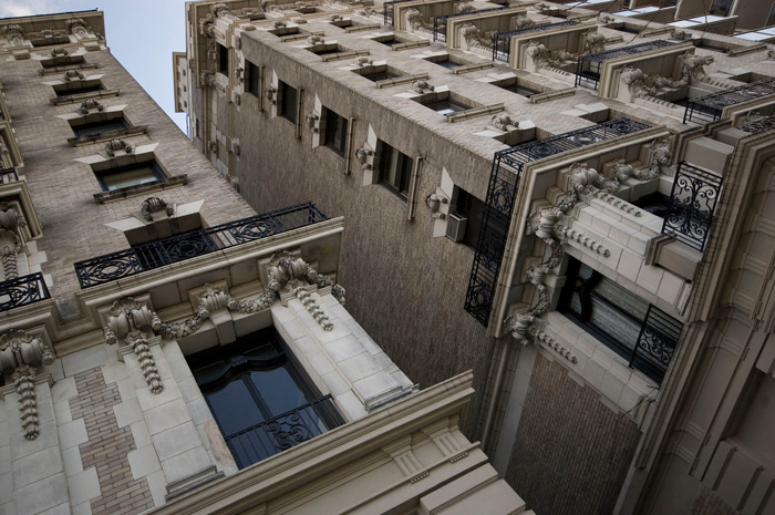 A pair of white brick buildings, with Beaux Arts details surrounding its windows.