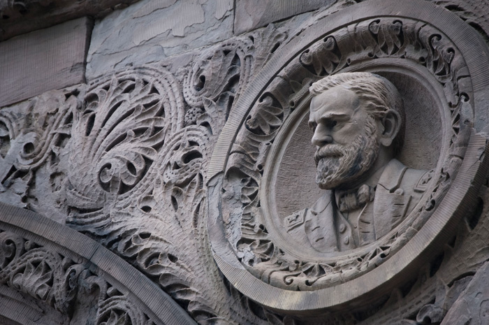 A relief shows Grant, in his garb as a general, amidst an ornate circle and other details on the side of a building.