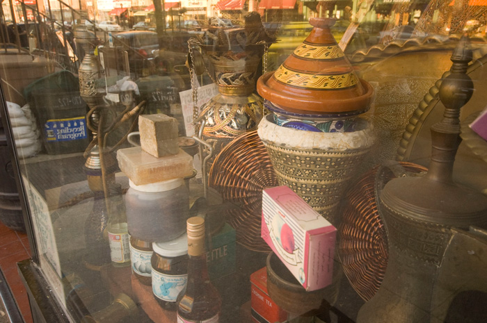 Behind the glass windows of a Middle Eastern deli are a tajine, a hookah, wicker, and a veriety of foods.