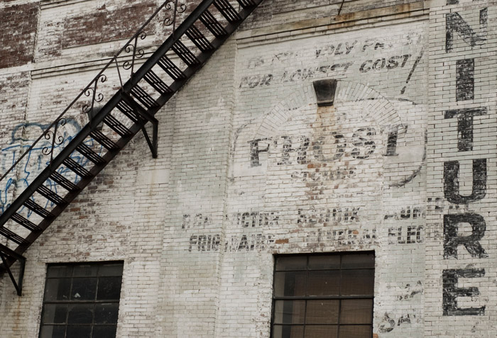 An old brick building's wall has the remnants of lettering advertising kitchen appliances.