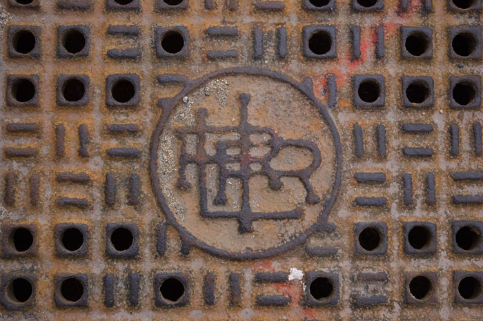 A manhole cover for the Long Island Rail Road has the initials 'LIRR' intricately intertwined.