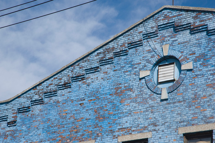 The blue paint on a brick building is starting to peel, but the sky is still blue!