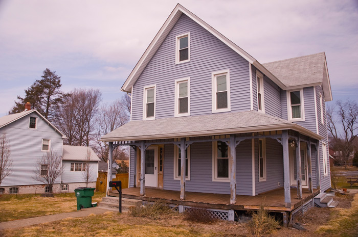 A two story house, with an attic, has a lovely porch front.