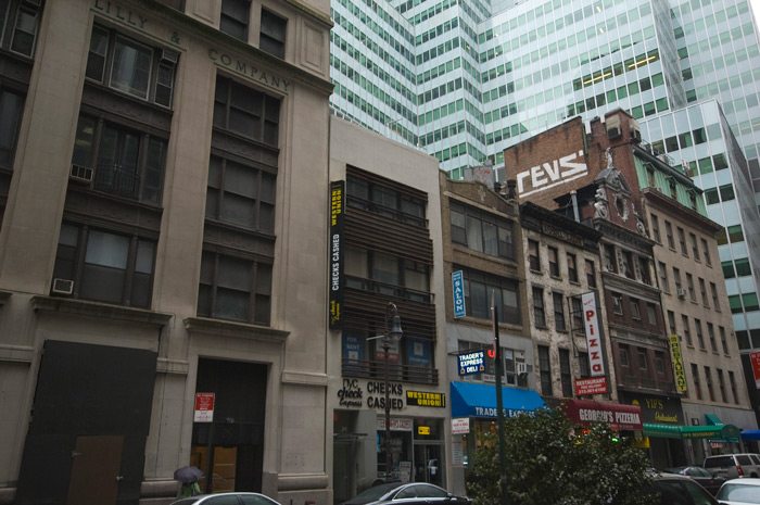 The graffiti artist 'Revs' has used a paint roller to leave a large 'tag' on the sie of a brick building dwarfed by glass towers.