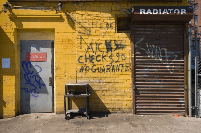 An auto repair business has a few of its prices spray-painted on its outer wall, messily.