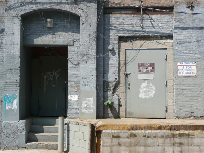 Two doors in a grey industrial wall, with all sorts of wiring going this way and that.