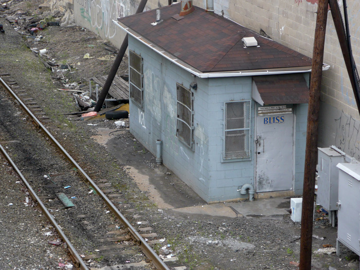 A shed next to a railroad track has the word 'Bliss' painted on its door.