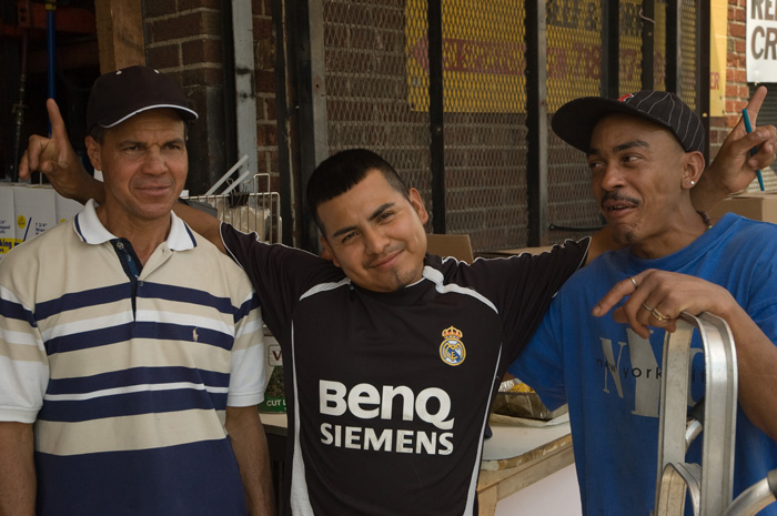 Three guys in a row, smiling over the idea of having their photo taken by strangers.