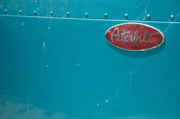 A red plastic oval for Peterbilt trucks is on a turquoise truck.