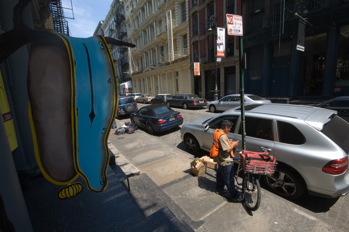 A bike messenger makes an entry into his record book, and a Salvador Dali 'melting clock' hangs nearby.