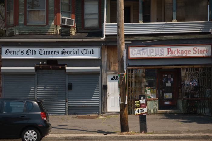 One storefront, closed, is for an old social club; next to it is an open liquor store.