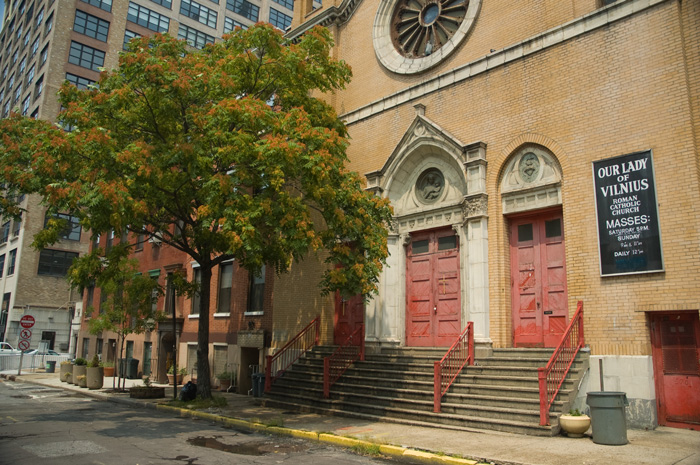 A yellow brick church sits on an isolated block, with no one in sight.