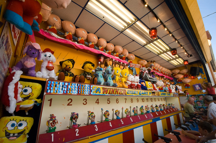 Rows of colorful prizes tempt kids to an amuesement park shooting range.