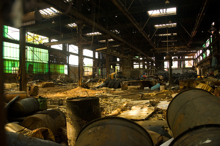 The inside of a low building is filled with sand and debris; the roof and many windows are missing.