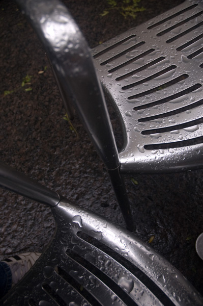 Rain drops make two chrome chairs seem unwelcoming.