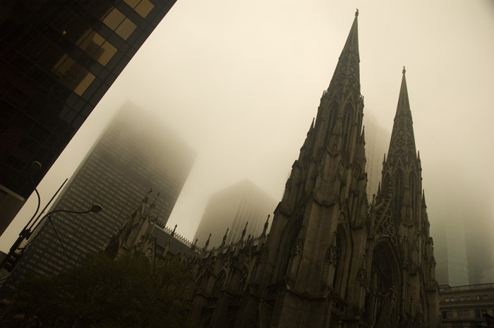 The spires of St. Patrick's Cathedral compete with the fog, which has obscured skyscrapers at the rear.