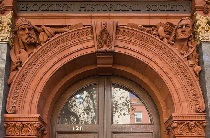 Two heads, representing North America's past, peer down over an archway