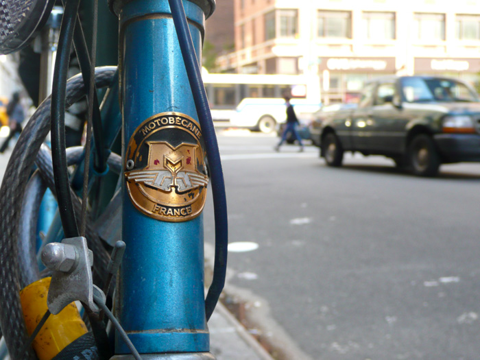 A blue bicycle'shead badge shows clearly, while the street scene bebehind it is all a blur.