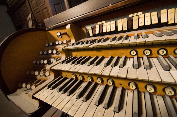 The keyboard of an old organ is covered in dust.