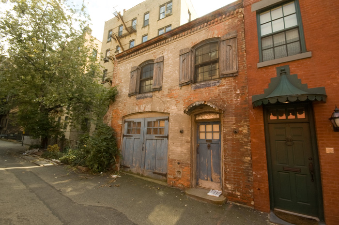 A row of houses on a dead end lane have exposed brick, and the architecture indicative of having once been stables.