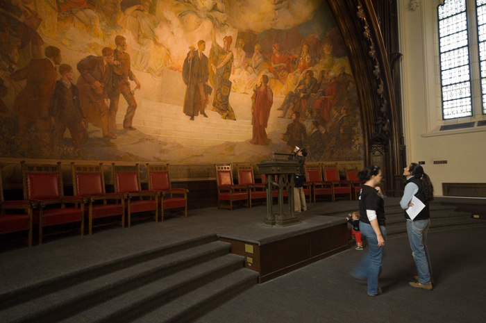 People gaze at a mural depecting a graduate going on to a better world.