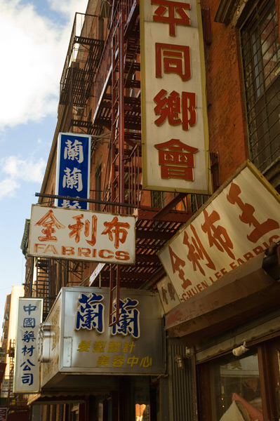 Old signs, mostly in Chinese but with some English, cling to an old brick building.