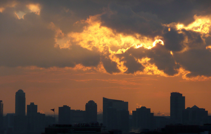 A sun hides behind clouds as it begins to set.