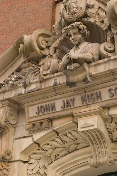 An ornate sculpture above an entrance includes a boy with his hands crossed.