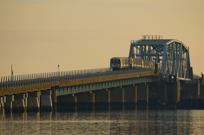 An 'A' train snakes across a birdge from the Rockaways, in the grey twilight of late afternoon.