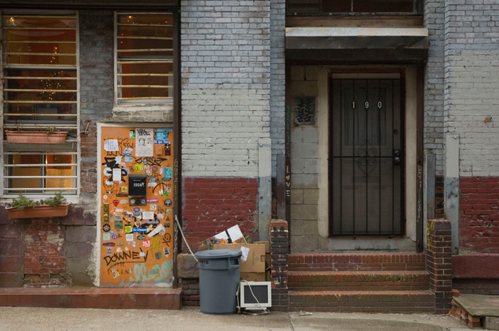 Two very different doors: one a beech color and covered in stickers, the other all black.