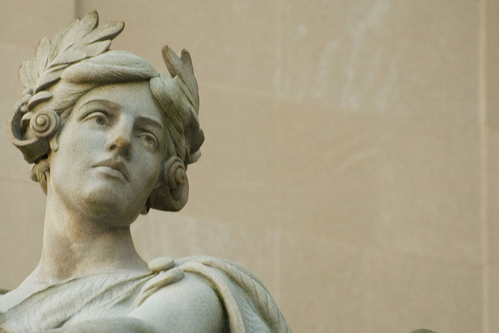 A statue head, with a laurel wreath, looks off to the right.