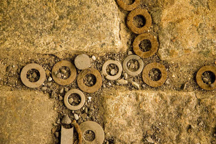 Washers of various sizes, and grit and pebbles, have settled in the cracks between paving stones.