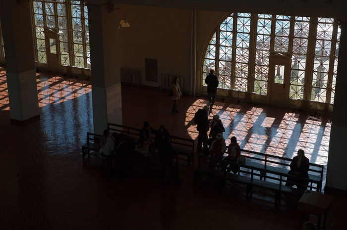 People are silhouetted against an arced window with many panes.